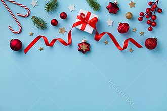 Gift or present box and holiday decorations on blue background top view. Christmas or New year greeting card. Flat lay style