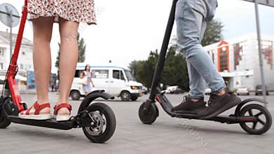 Man and woman legs ride future technology electric scooters