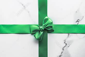 Green silk ribbon and bow on marble background, St Patricks day present or Christmas glamour gift decor for luxury digital brand,