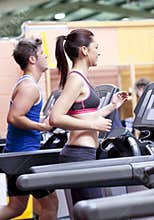 Pretty woman with earphones using a treadmill