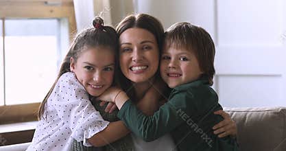 Loving mommy and cute children embracing laughing looking at camera