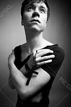 Young man in modern black clothing holding big black cross in hands