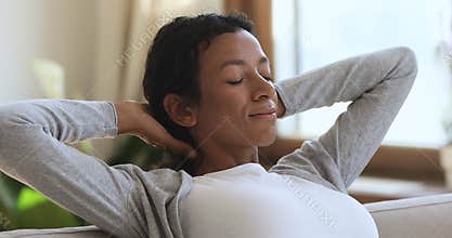 Relaxed african woman resting on comfortable sofa dreaming at home