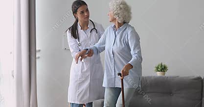 Young woman nurse caregiver help senior grandmother hold cane stick