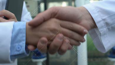 Two professional scientists shaking hands, lab research cooperation, contract