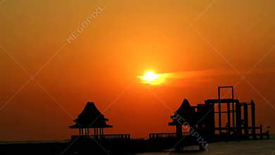Sunset pass orange cloud and silhouette two abandon pavilion in sea