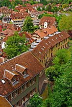 View of typical building architecture layered between many green trees behind Bern Parliament