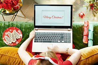 Modern little princess writing Merry Christmas email on laptop