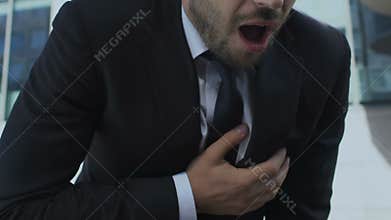 Exhausted business man having heart attack in street, chest pain, stressful life