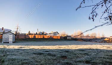 A plot of land with a lawn for the construction of a house or territory for grazing farm animals in frosty sunny morning