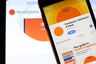 Mobile phone with Headspace Meditation & Sleep icon on screen close up with website on laptop