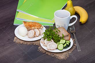Protein breakfast with chiken, bread, egg before school, work, university on the wooden background with books