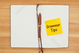 Grammar tips message on sticky note in a journal with a pen