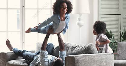 Happy afro american father and kids playing in living room