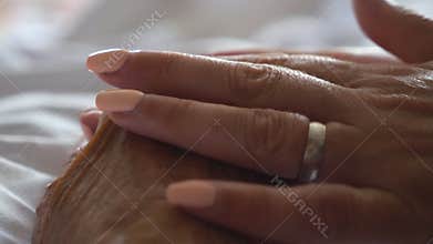 Close up hand of young woman gentle stroking her sick mother giving support. Daughter comforting wrinkled arm elderly