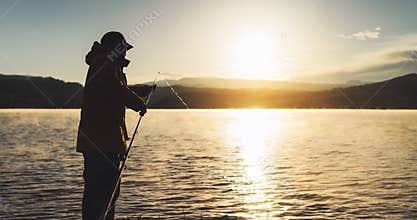 Outline fisherman fishing rod at sunrise sunlight, man enjoy hobby on evening lake, person catch fish on background night