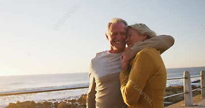 Senior couple embracing each other alongside beach