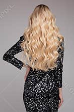 Portrait Of Beautiful Young Blond Woman With Long Wavy Hair. Back View