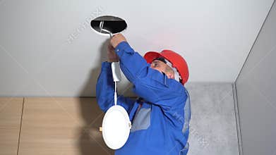Electrician with red helmet checking lighting led panel at home