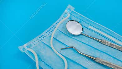 Professional Dental Instruments: Mouth Mirror and Dental Explorer On Blue Face Mask