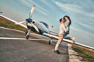 Young happy couple is having fun on runway near airplane