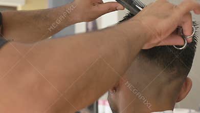 Barber cuts hair of client with scissors