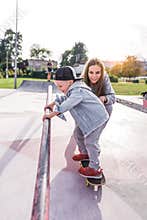 Woman mother, parent, help and support in training, little boy 4-5 years old, learns to ride skateboard, in summer on