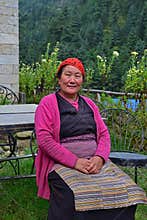 Elderly Sherpa woman who works in a local hostel in traditional attire sitting in the home garden