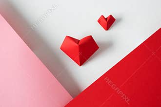 Two origami hearts on white background and pink and red paper borders; above. Creative postcard for Valentine`s day