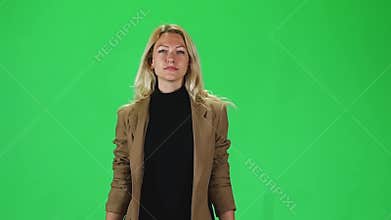 Blonde girl in a black turtleneck and stylish brown jacket going against a green screen. Slow motion