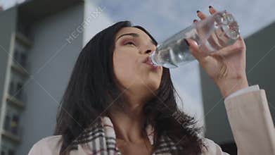 Businesswoman drinking water from bottle on street. Girl enjoying fresh water