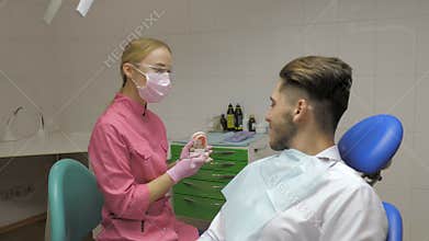 Female dentist with male patient doing the cleaning of the tooth in dentistry