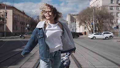 Curly girl fun dancing walking around the city. carefree teenager is smiling and having fun.