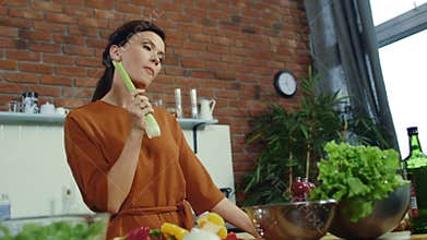 Girl eating fresh celery at home. Young woman getting idea during cooking.