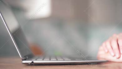 Women`s hands open the laptop and lift its lid to start working at home close-up. Remote learning at home via a laptop