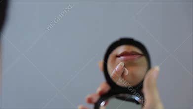 Woman apply cream to a pimple on her face in the mirror. Close up. Acne, redness, blemish, blackheads. Skin care, cosmetology. Tee