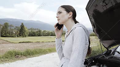 Young woman with broken car calling roadside assistance