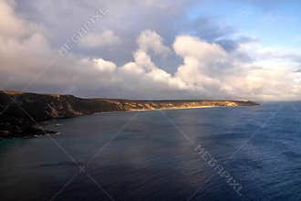 Clouds over the rocky shore, partly illuminated by the sun. Australia