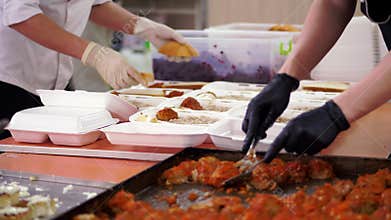 Close-up, Volunteers pack free hot meals in lunchboxes, to be delivered to poor and homeless people during lock down of