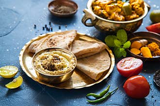 Oriental food - Indian homemade bread chapati and sauce. indian cuisine. Indian Curry in copper brass with ingredients in blue