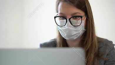 Young woman working at laptop computer in office mask during epidemic covid-19