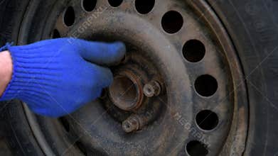 Car mechanic unscrews the wheel bolts.