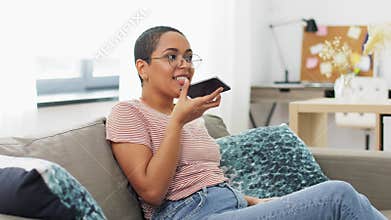Woman recording voice with smartphone at home
