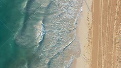 Aerial drone view flying over azure waves and sand beach, no people