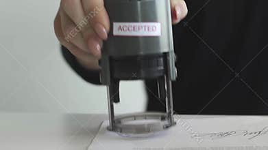 Female hand that puts an ACCEPTED stamp in the contract or documents.