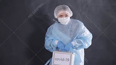 Woman with a metal suitcase in her hands throws her legs in different directions dancing. The case is marked covid-19. Smoke envel