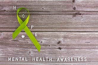 Lime green ribbon. Mental health awareness month concept mental health letters on old aged wooden background with