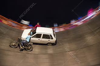 Panning shot of  bike and car driving inside death well