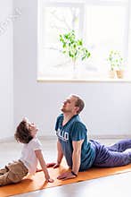 Dad son do sport at home. The father teaches child a healthy lifestyle. Parenthood