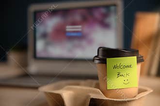 Back to Work Concept. Closeup of Welcome Note on Takeaway Coffee Cup in Office Desk